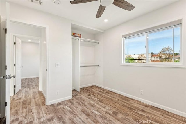 unfurnished bedroom with light hardwood / wood-style flooring, a closet, and ceiling fan