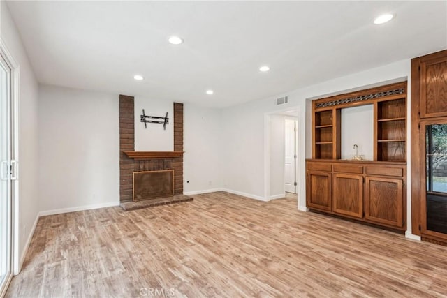 unfurnished living room with sink, a fireplace, and light hardwood / wood-style floors