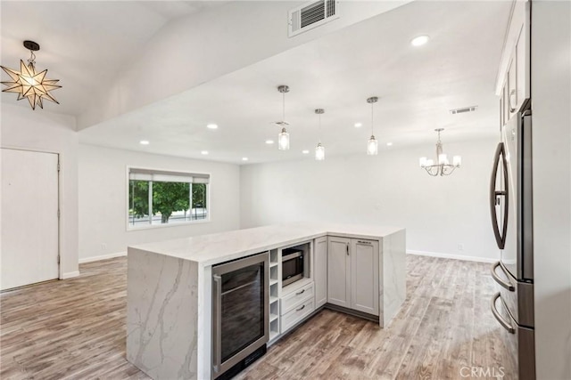 kitchen with hanging light fixtures, appliances with stainless steel finishes, wine cooler, and a chandelier