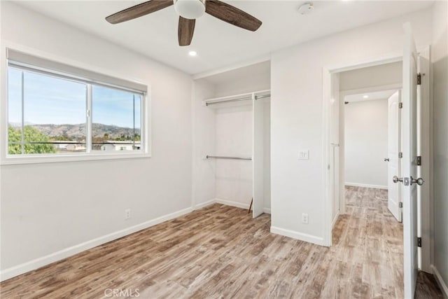 unfurnished bedroom featuring ceiling fan, light hardwood / wood-style floors, and a closet