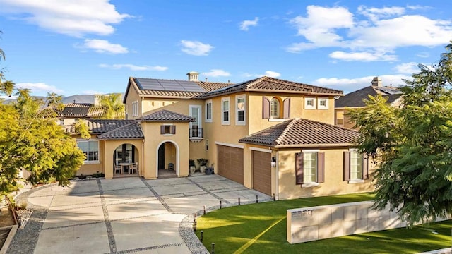 back of house with solar panels, a yard, and a garage