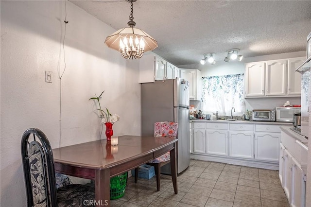 1119 E Colon St, Wilmington, CA 90744 - kitchen with stainless steel appliances, a chandelier, white cabinetry, light tile patterned flooring, and hanging light fixtures