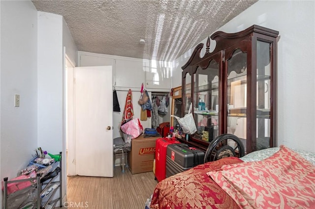 bedroom featuring a textured ceiling, a closet, light hardwood / wood-style flooring, and multiple windows