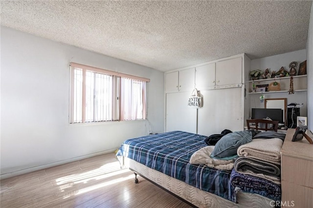 bedroom with light wood-type flooring and a textured ceiling