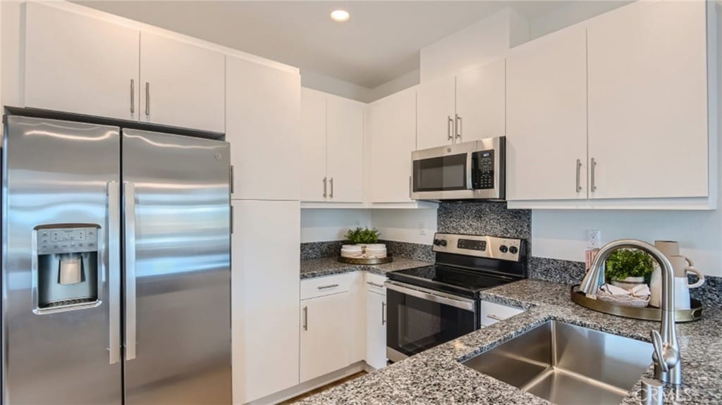 kitchen featuring sink, white cabinetry, stainless steel appliances, and dark stone counters