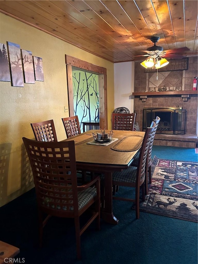 dining area with carpet flooring, ceiling fan, a fireplace, and wooden ceiling