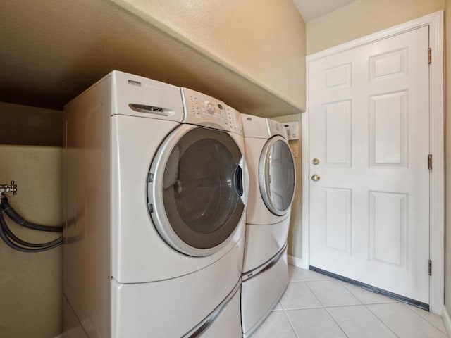 clothes washing area featuring washer and clothes dryer and light tile patterned floors