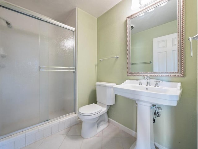 bathroom featuring toilet, a shower with door, and tile patterned flooring