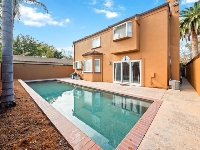 back of property featuring a patio area and a fenced in pool