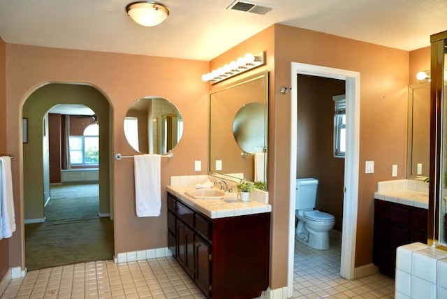 bathroom with toilet, vanity, and tile patterned flooring