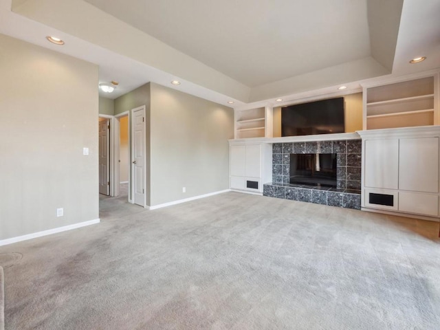 unfurnished living room featuring built in features, a tiled fireplace, and carpet