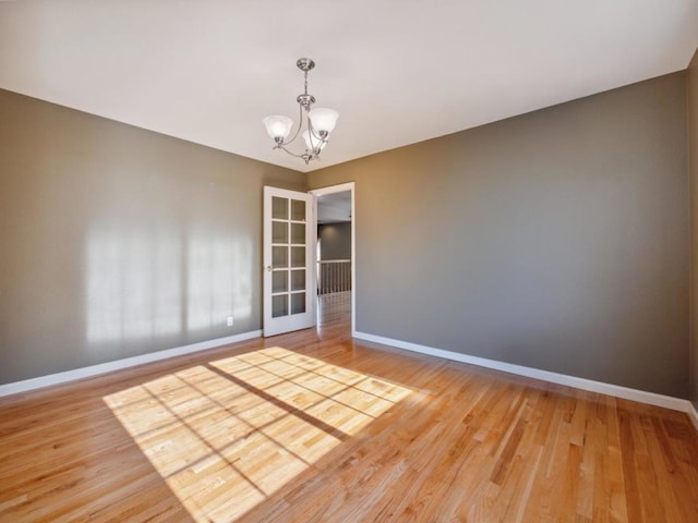 spare room with hardwood / wood-style floors and an inviting chandelier