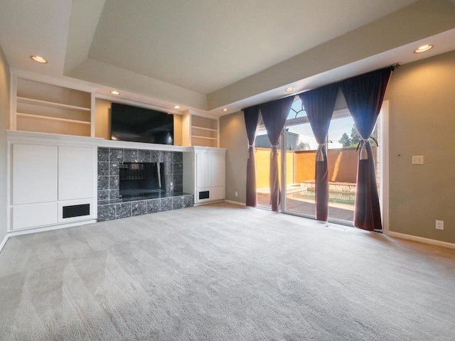 unfurnished living room with built in features, a tile fireplace, and light carpet