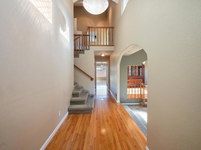 corridor featuring a high ceiling and light wood-type flooring