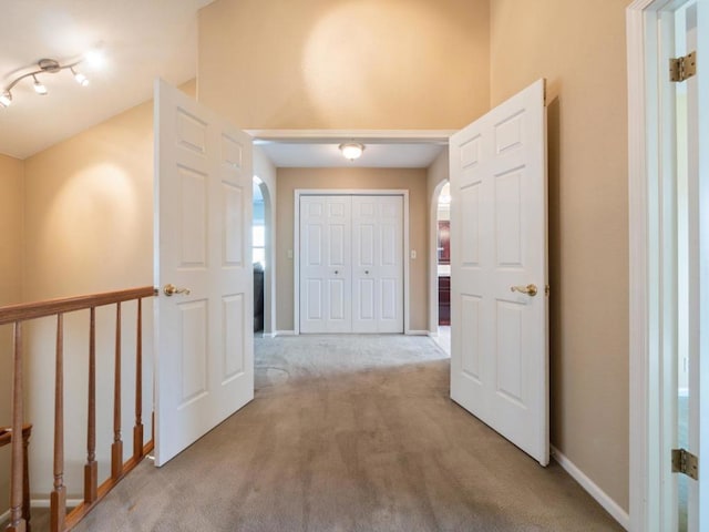 corridor featuring vaulted ceiling and light colored carpet