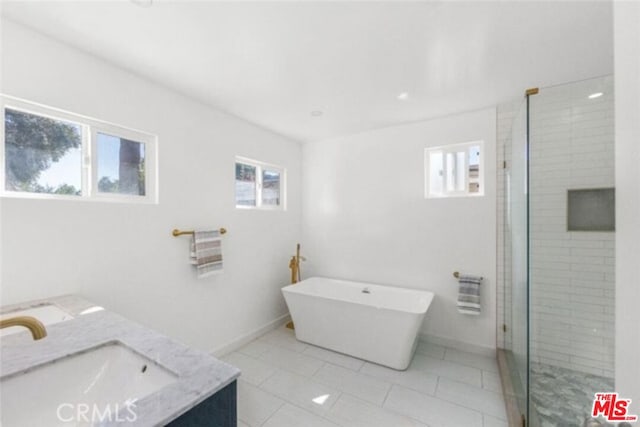 bathroom featuring plus walk in shower, vanity, tile patterned floors, and a healthy amount of sunlight