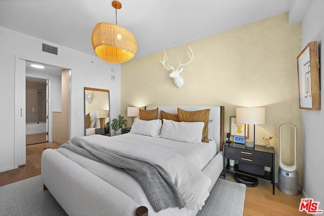 bedroom featuring connected bathroom and hardwood / wood-style floors