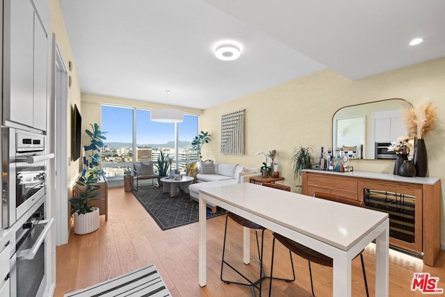 kitchen featuring light hardwood / wood-style floors, oven, pendant lighting, and wine cooler