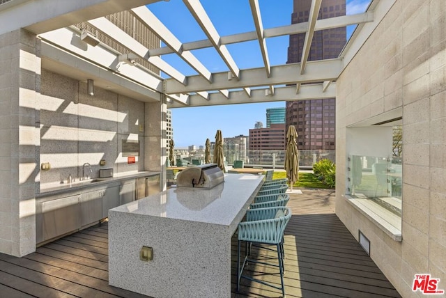 wooden deck featuring exterior kitchen, grilling area, a wet bar, and a pergola