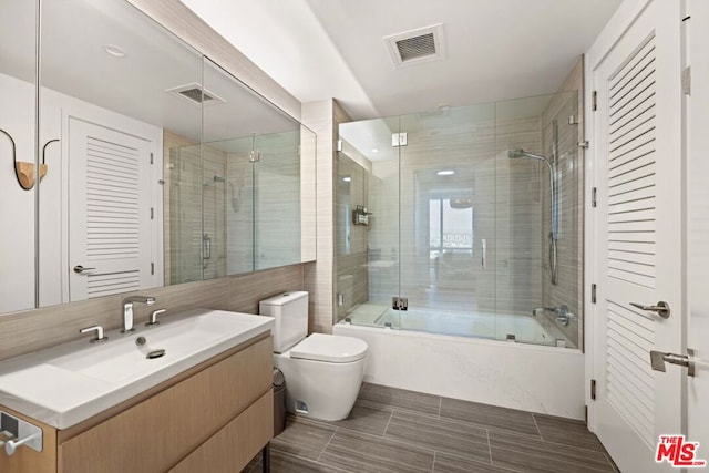 full bathroom featuring shower / bath combination with glass door, vanity, and toilet