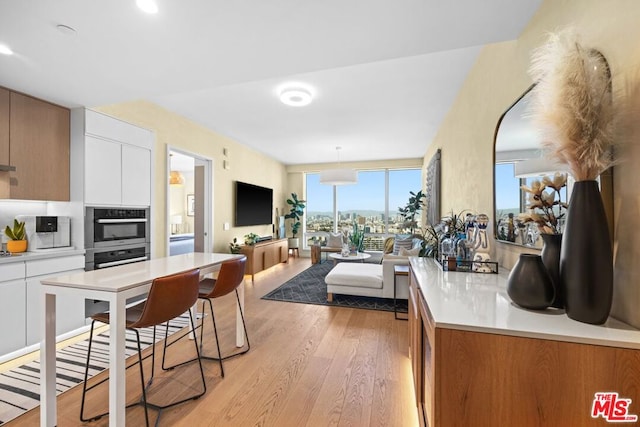 kitchen with white cabinets, light hardwood / wood-style floors, pendant lighting, and oven