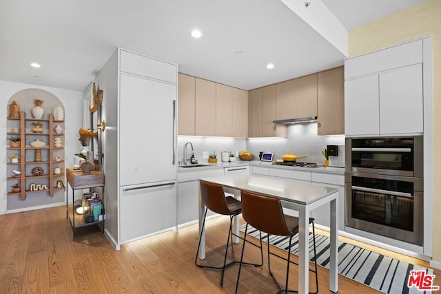 kitchen featuring light hardwood / wood-style floors, gas cooktop, sink, and double oven