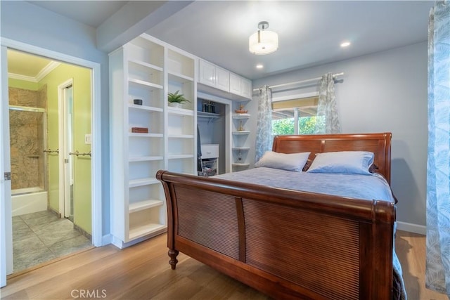 bedroom with light wood-type flooring, ensuite bath, a closet, and ornamental molding