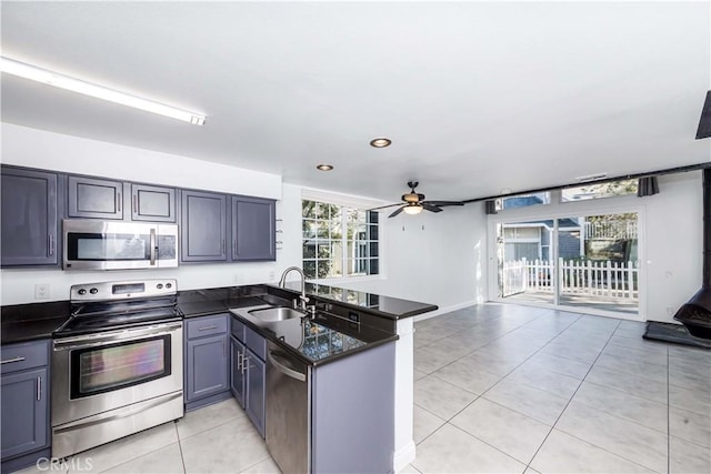 kitchen with kitchen peninsula, ceiling fan, appliances with stainless steel finishes, light tile patterned flooring, and sink