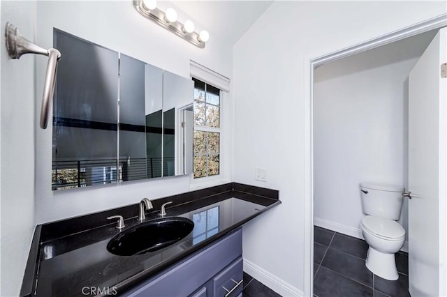 bathroom with toilet, vanity, and tile patterned flooring