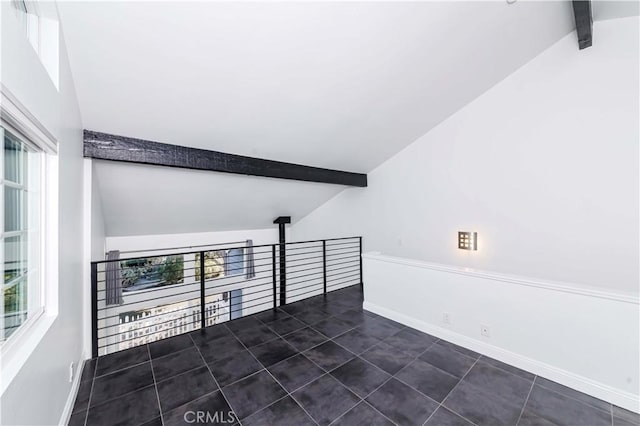 tiled spare room featuring vaulted ceiling with beams