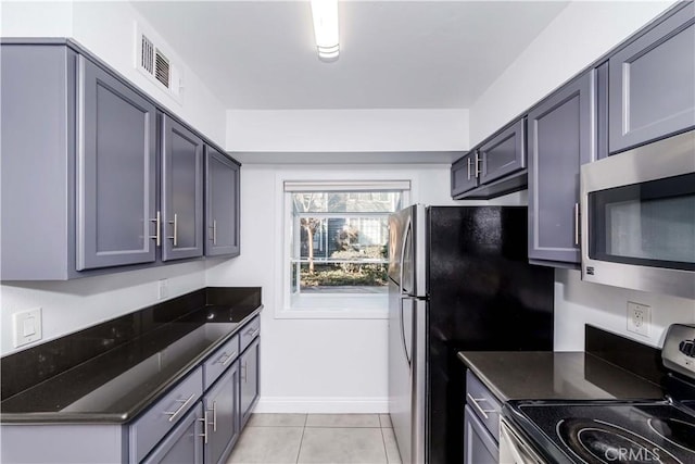 kitchen with light tile patterned flooring, appliances with stainless steel finishes, and gray cabinetry