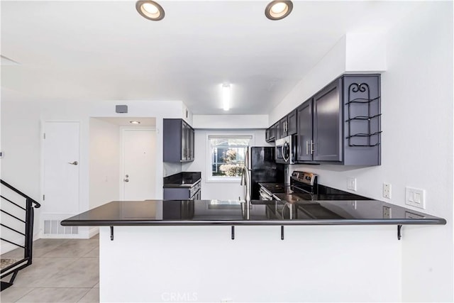 kitchen featuring a breakfast bar, kitchen peninsula, appliances with stainless steel finishes, and light tile patterned flooring