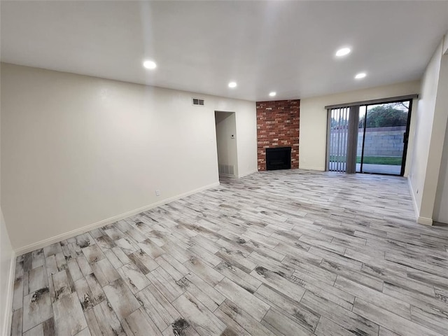 unfurnished living room with light hardwood / wood-style floors and a brick fireplace