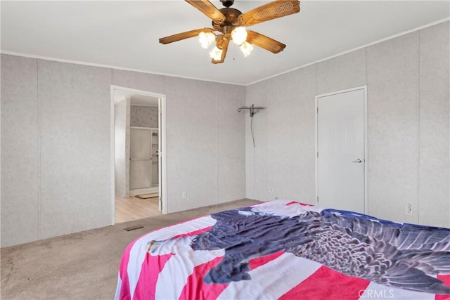 bedroom featuring connected bathroom, light hardwood / wood-style flooring, ceiling fan, and crown molding