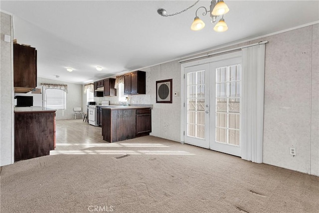 kitchen with french doors, decorative light fixtures, light colored carpet, dark brown cabinetry, and a chandelier