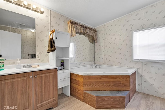 bathroom featuring a tub, hardwood / wood-style floors, vanity, and ornamental molding