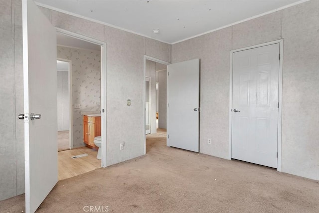 unfurnished bedroom with light carpet, connected bathroom, and ornamental molding