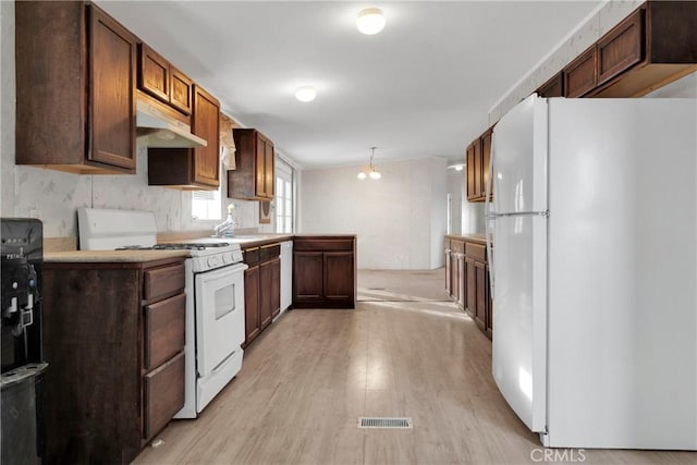 kitchen with backsplash, white appliances, sink, light hardwood / wood-style flooring, and hanging light fixtures