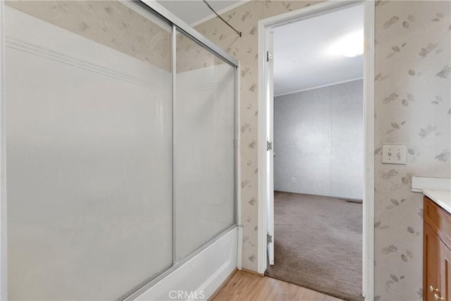 bathroom featuring hardwood / wood-style flooring, vanity, and bath / shower combo with glass door