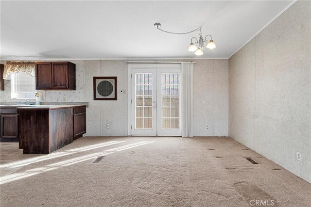 kitchen featuring light colored carpet, a healthy amount of sunlight, and a notable chandelier