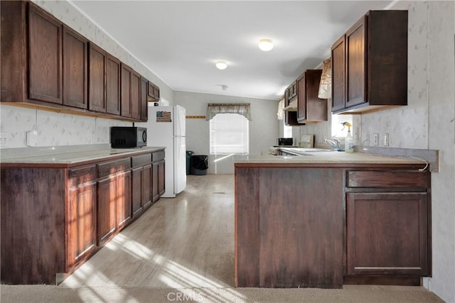 kitchen with dark brown cabinets, white refrigerator, light hardwood / wood-style flooring, and lofted ceiling