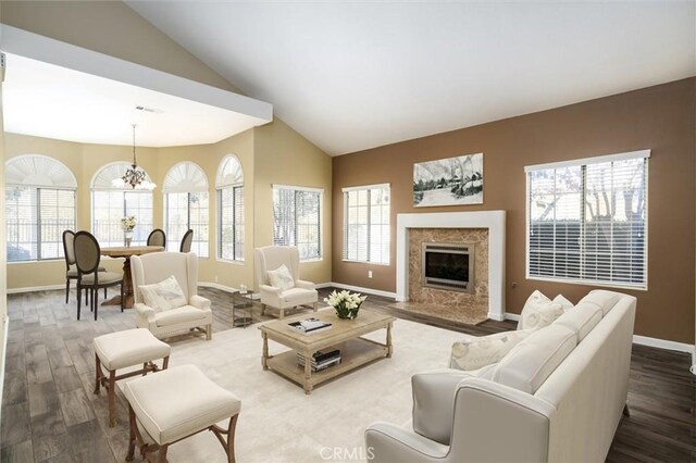 living room with a premium fireplace, a healthy amount of sunlight, hardwood / wood-style flooring, and a notable chandelier