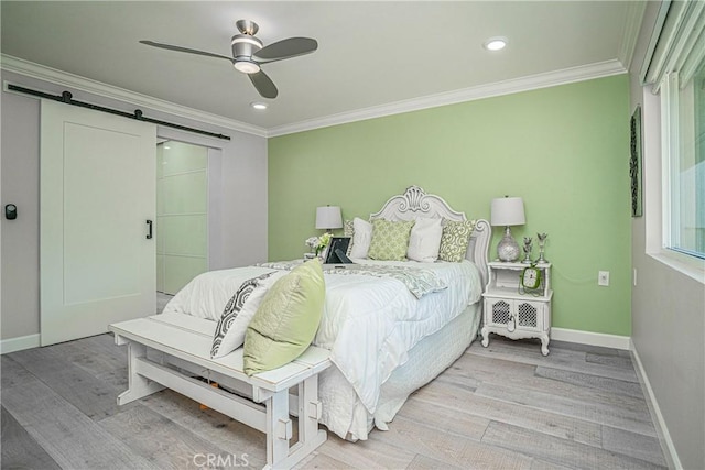 bedroom featuring ceiling fan, crown molding, a barn door, and light hardwood / wood-style floors