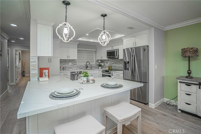 kitchen featuring white cabinets, stainless steel appliances, sink, light stone counters, and crown molding