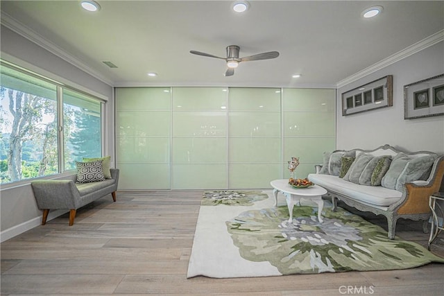 living area with ceiling fan, ornamental molding, and light hardwood / wood-style floors