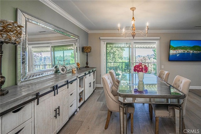 dining area with an inviting chandelier, ornamental molding, and light hardwood / wood-style flooring