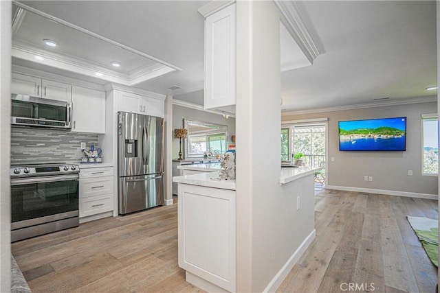 kitchen with tasteful backsplash, white cabinetry, light hardwood / wood-style flooring, appliances with stainless steel finishes, and ornamental molding