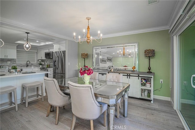 dining area with a chandelier, crown molding, light hardwood / wood-style floors, and sink