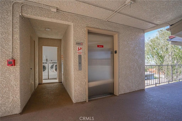 corridor featuring washing machine and clothes dryer and elevator