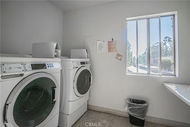 clothes washing area with a healthy amount of sunlight and washing machine and clothes dryer